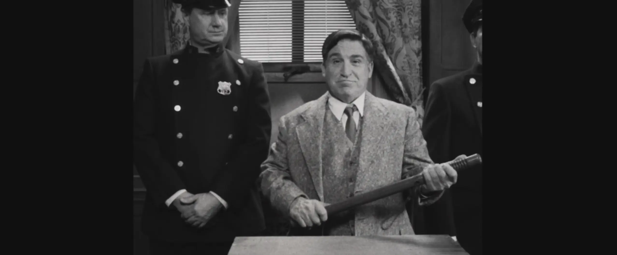 Black and white vintage scene of man in suit holding baseball bat with officers